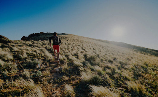 A trail runner in a grassy, natural environment.