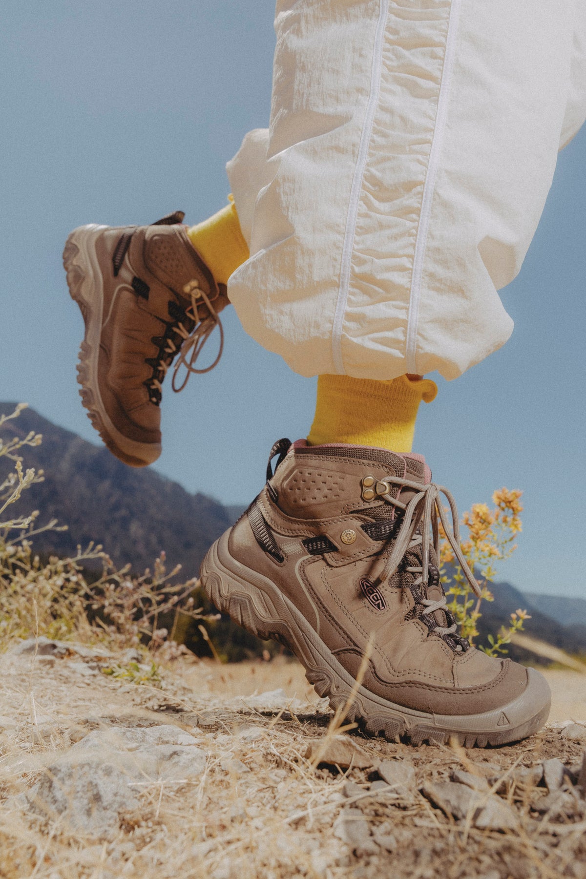 A close-up outdoor shot of a person wearing tan keen targhee IV hiking boots with yellow socks