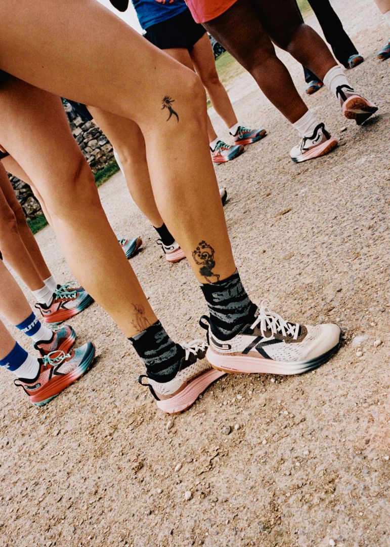 Close-up of people's legs wearing Seek trail running shoes and socks on a dirt path.