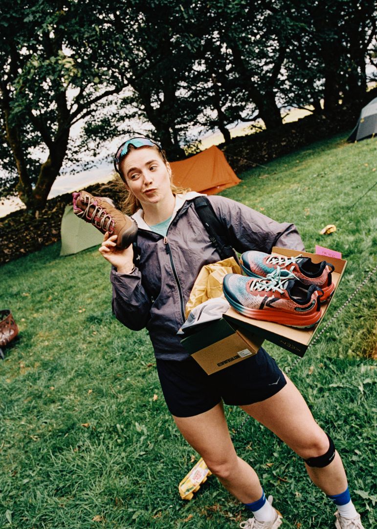 Person holding seek trail running shoes and a targhee iv boot outdoors on grass.