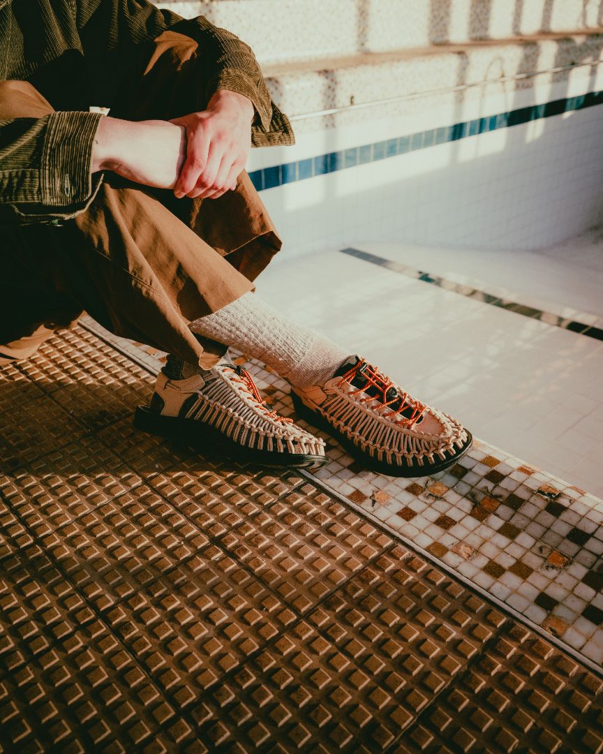 Person wearing uneek sandals on a tiled floor with a neutral color palette