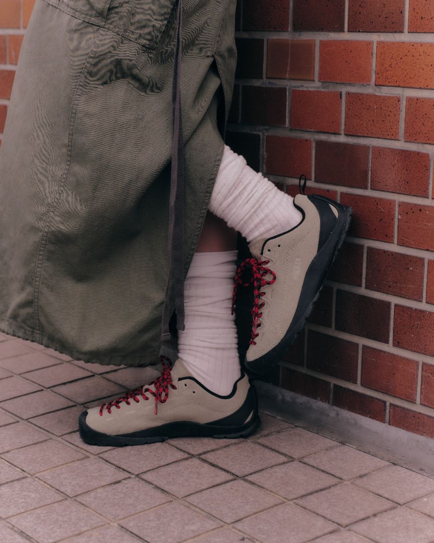 A person wearing beige trainers with red laces