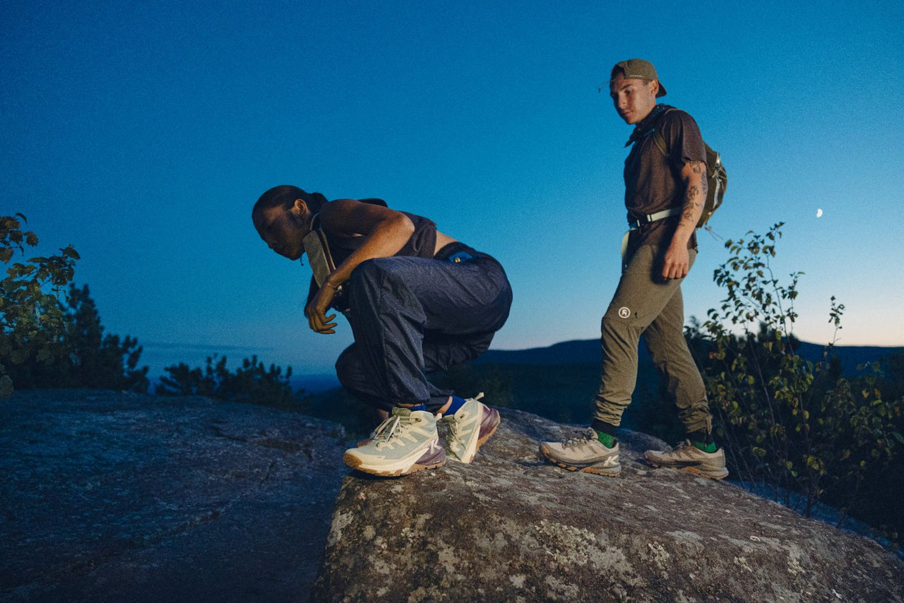 Two people on a rock at night with a clear blue sky wearing the targhee apex boot in light grey 