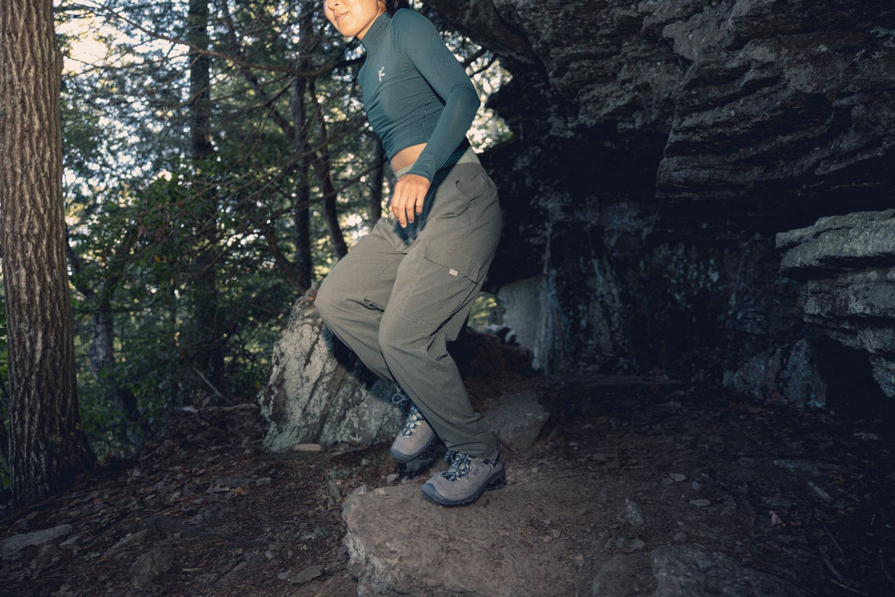 Person hiking in a forest, wearing green hiking pants and grey Keen Targhee hiking boots