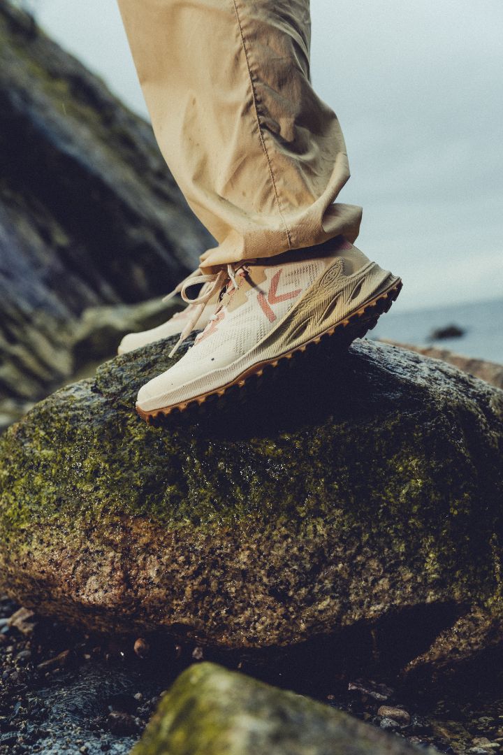 Person wearing Keen Zionic NXT hiking shoes and pants standing on a rock with a natural background