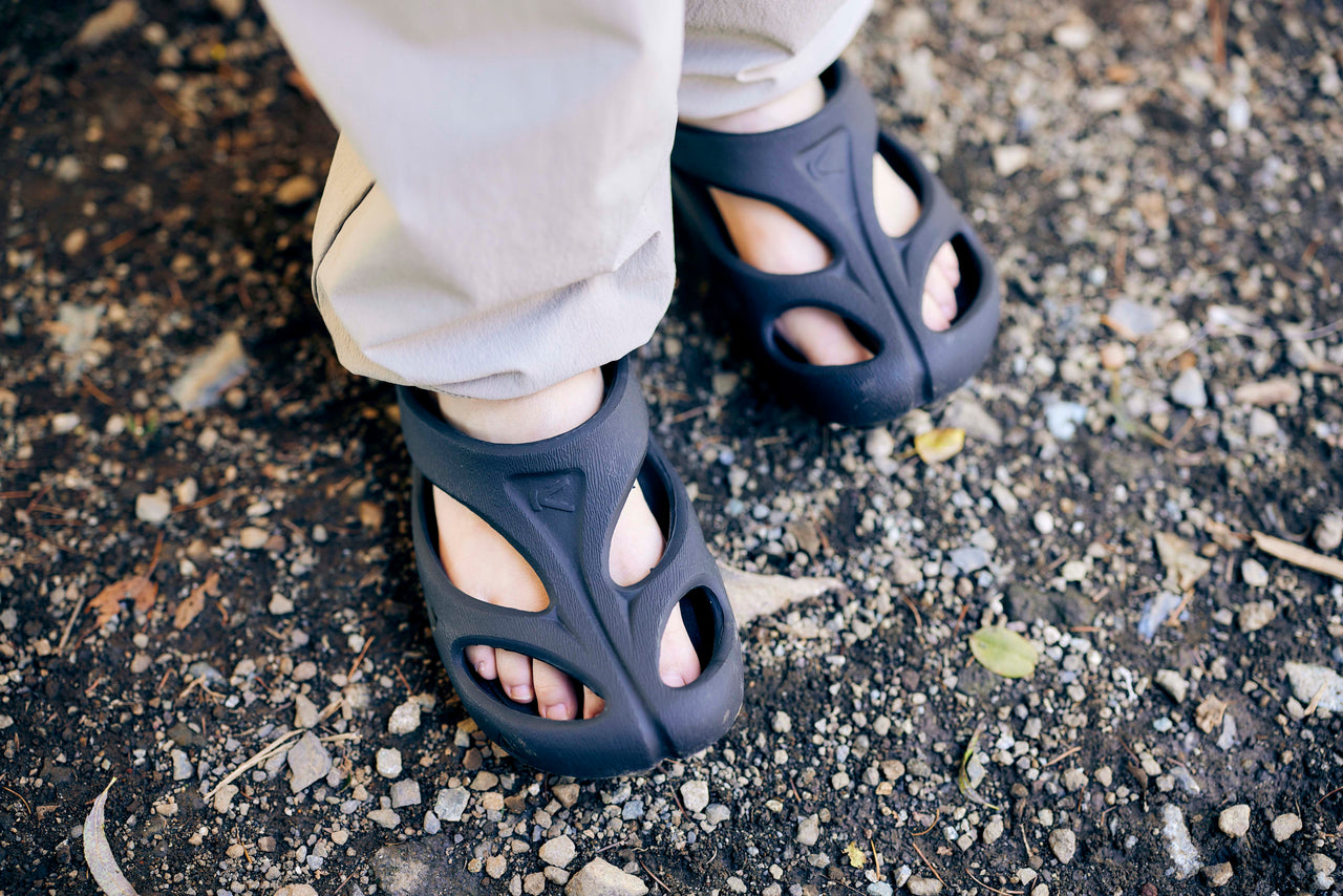 person wearing black slip-ons on a dirt track