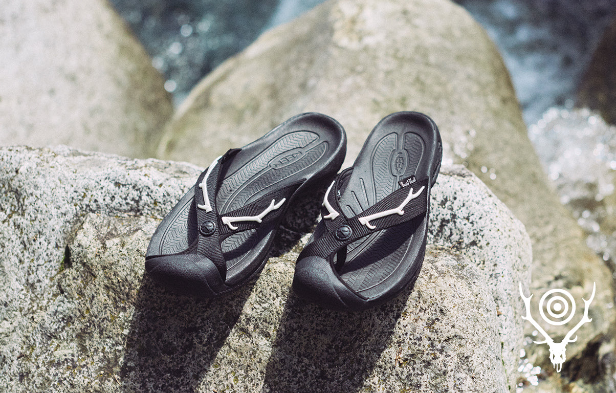 Black flip-flops on a rock with water in the background