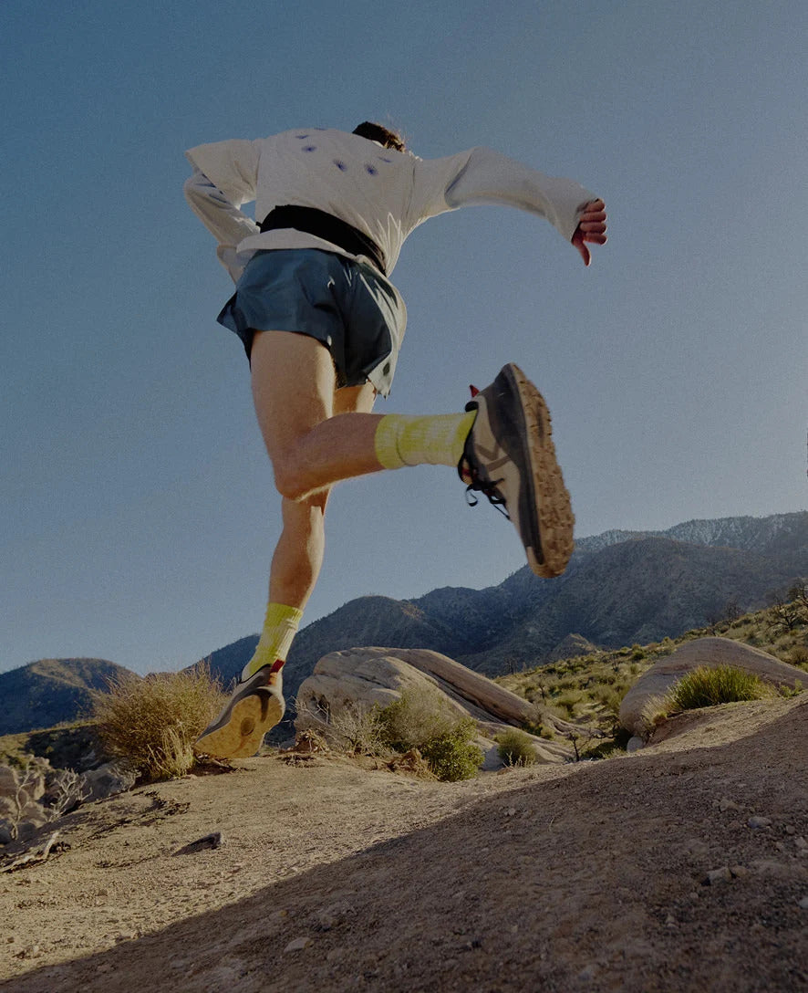 Person running on a rocky trail with mountains in the background