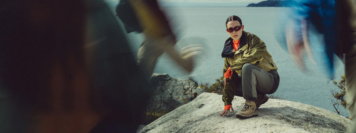 Woman crouching on coastal rock wearing tan waterproof hiking boots