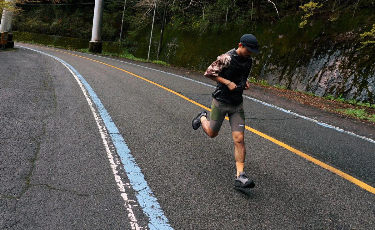 Person running on a road with a natural landscape in the background