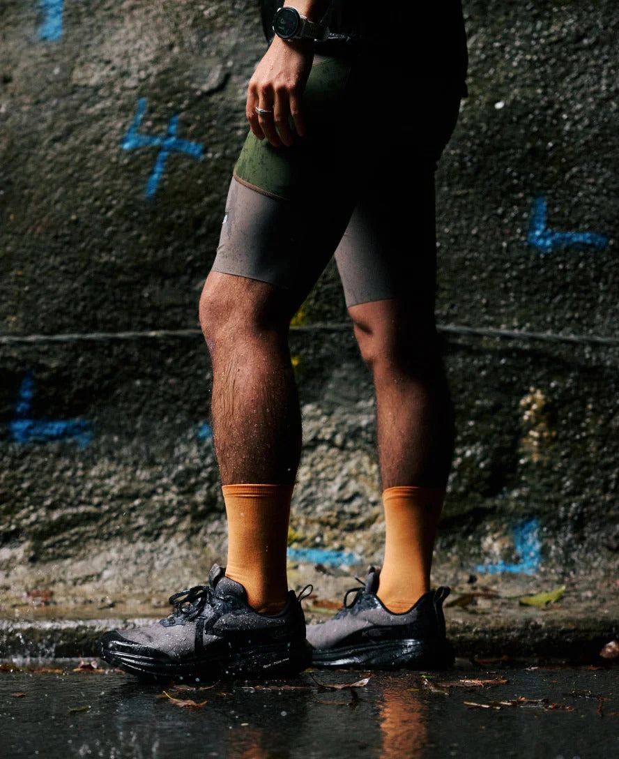 Person wearing cycling shorts and shoes against a graffiti-covered wall.