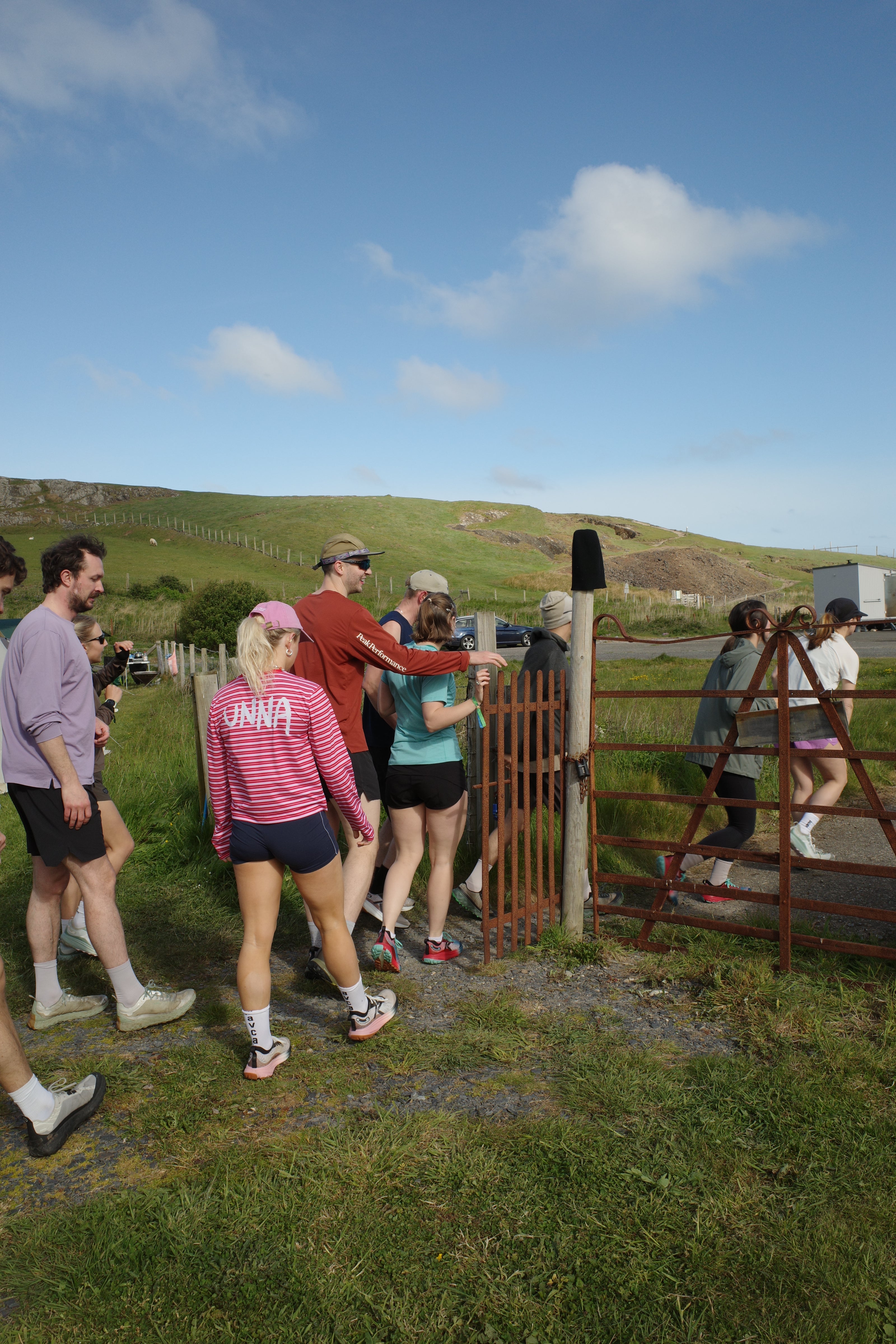 Group of people standing on a grassy area with a clear blue sky.
