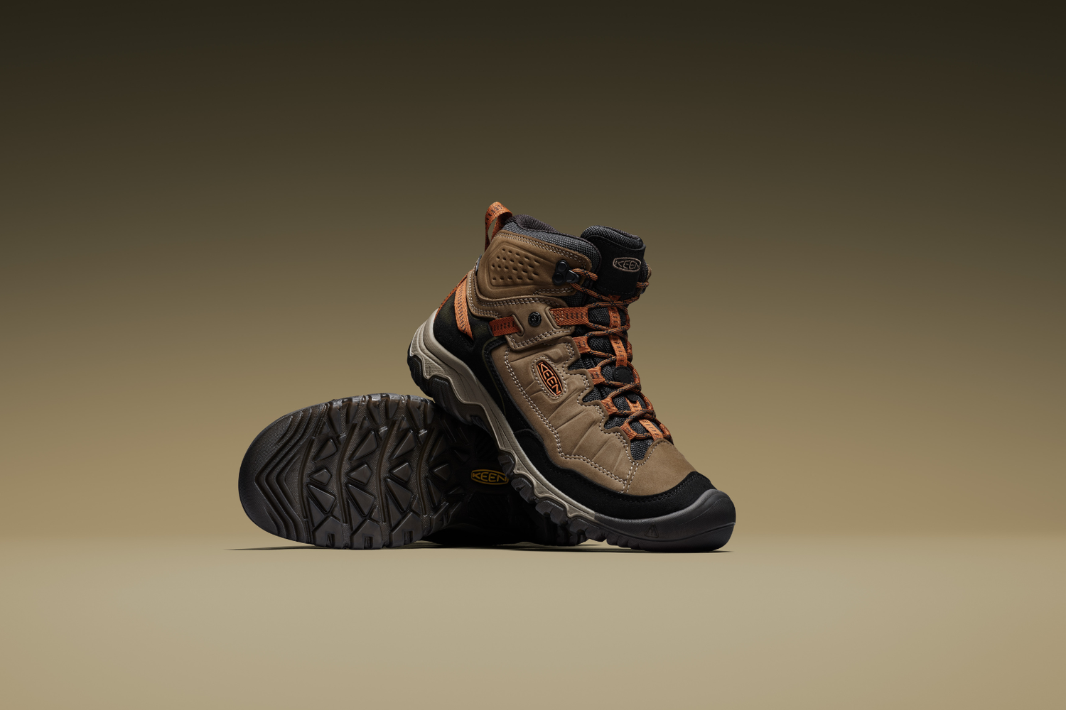 Pair of brown hiking boots with orange accents on a beige background
