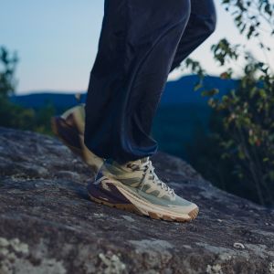 Person wearing hiking shoes on a rocky surface with a natural background
