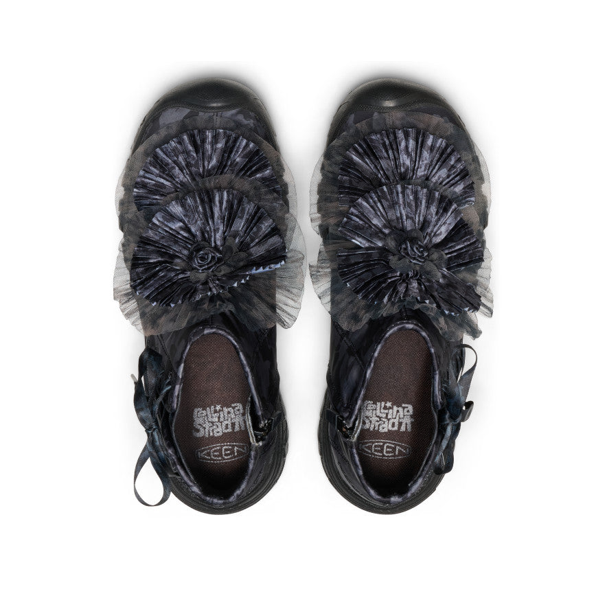 Top down view of a pair of black boots with  a floral decoration