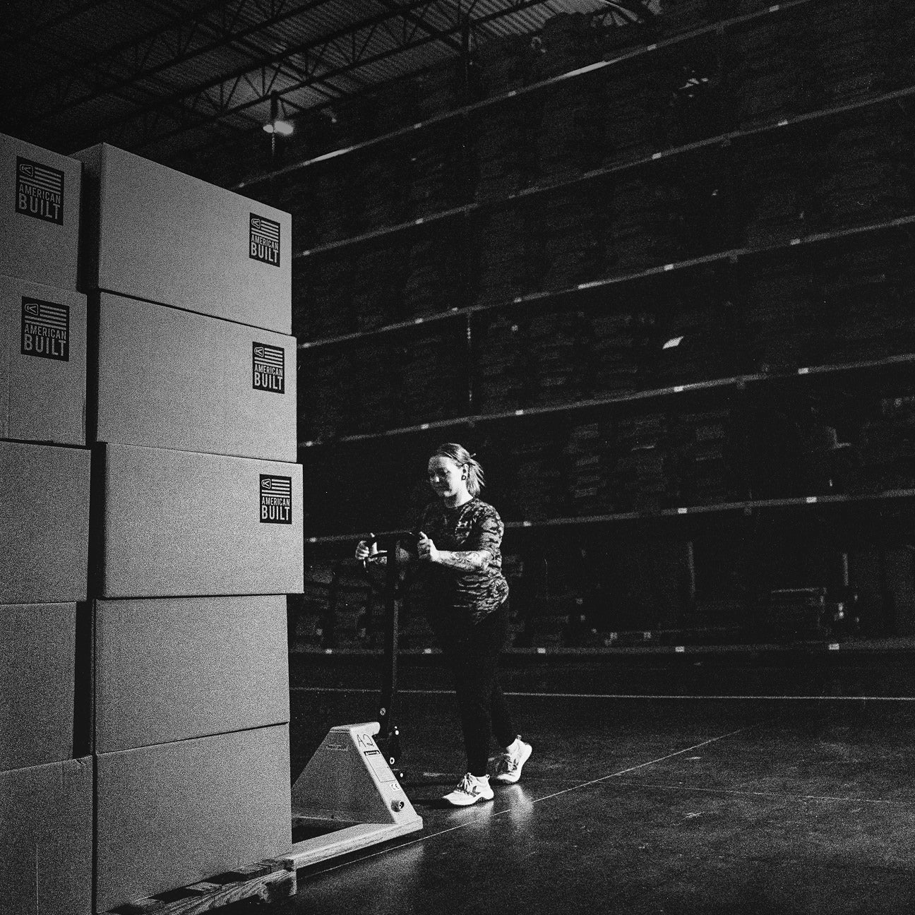 Person standing next to a stack of boxes in a warehouse setting