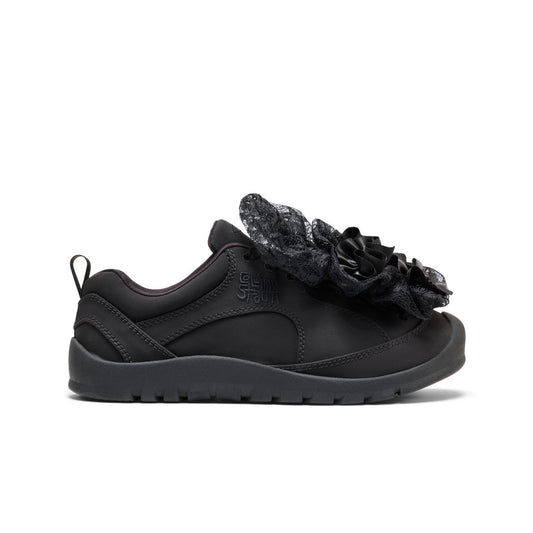 A black slip-on shoe with a textured black fabric flower decoration