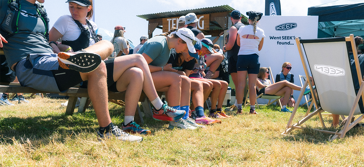 Outdoor scene at the love trails event, with multiple people sitting and standing on grass, wearing