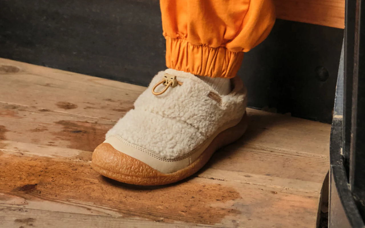 White slip-on shoe with brown sole on a wooden surface