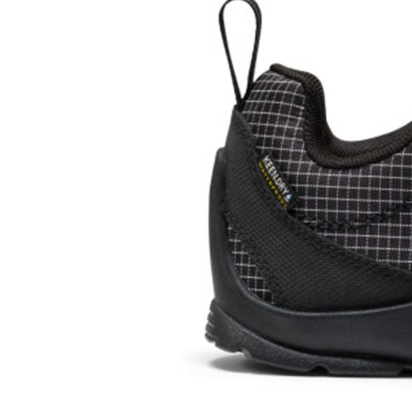 Close-up side view of a black outdoor shoe with a subtle grid pattern on the upper, a black sole, and a small K-SHORE label on the heel.