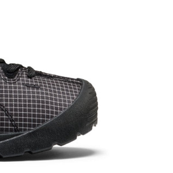Close-up of the toe and side of a black and gray checkered athletic shoe on a white background.