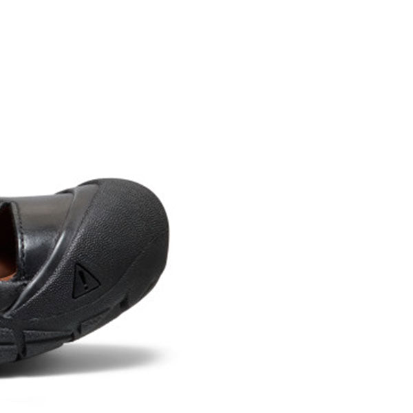 A close-up studio shot of the side of a black slip-on shoe, showing the textured upper and sole against a plain white background.