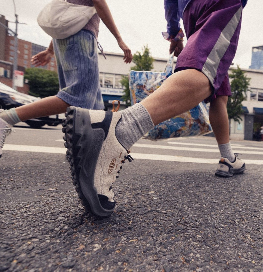 Close-up of a person's foot wearing a gray and black shoe on a street.
