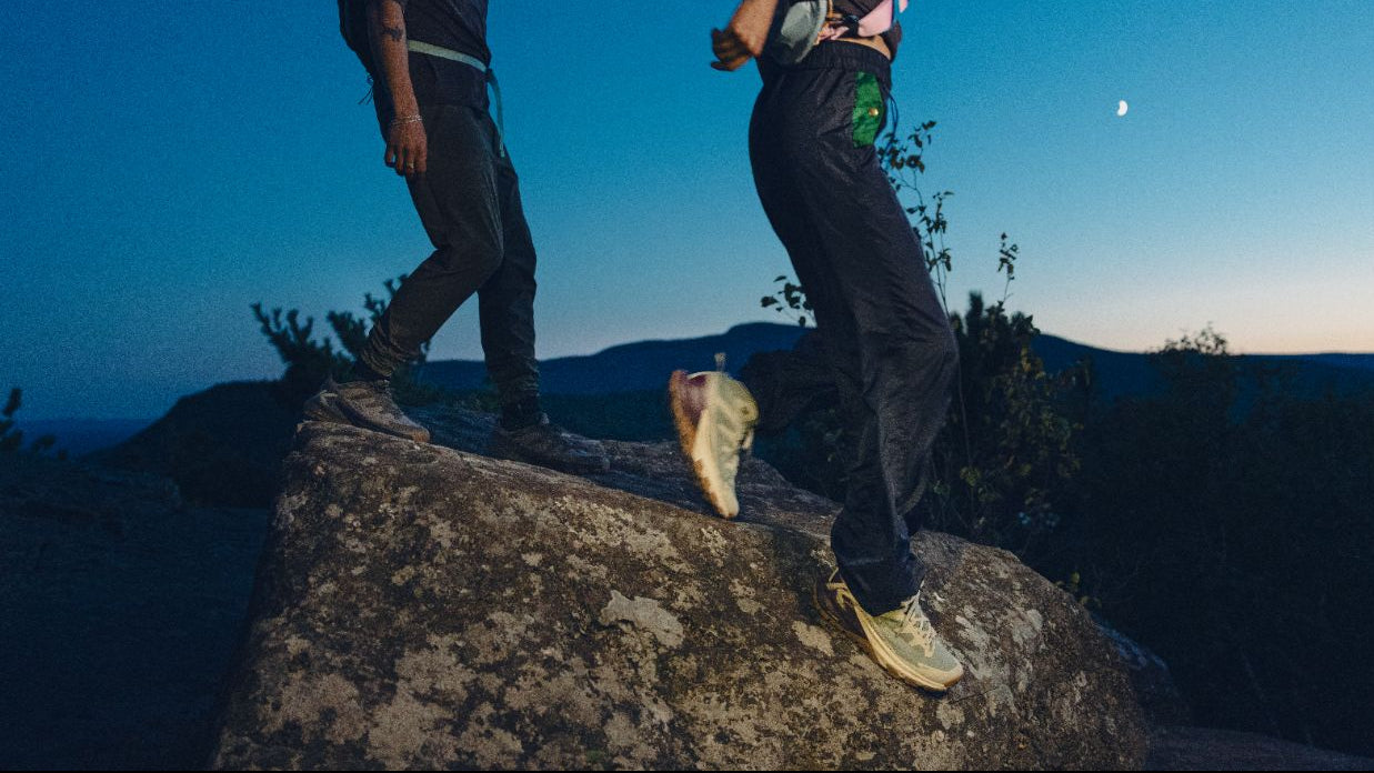 Two people standing on a rocky outcrop against a clear blue sky.