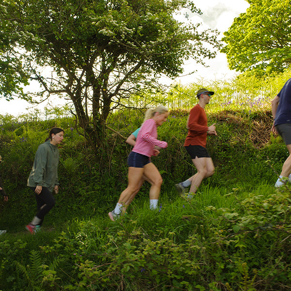 People running through a lush green forest path